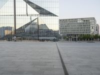 an empty plaza with several skyscrapers in the background and someone walking on the path