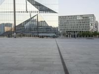 an empty plaza with several skyscrapers in the background and someone walking on the path