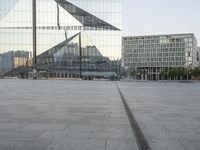 an empty plaza with several skyscrapers in the background and someone walking on the path