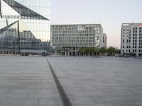 an empty plaza with several skyscrapers in the background and someone walking on the path