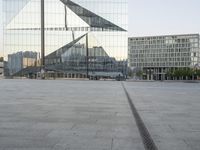 an empty plaza with several skyscrapers in the background and someone walking on the path