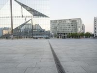 an empty plaza with several skyscrapers in the background and someone walking on the path