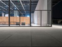 glass window with wooden wall at night near chairs and fireplaces outside with concrete floor