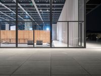 glass window with wooden wall at night near chairs and fireplaces outside with concrete floor