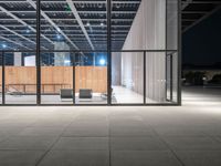 glass window with wooden wall at night near chairs and fireplaces outside with concrete floor