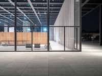 glass window with wooden wall at night near chairs and fireplaces outside with concrete floor