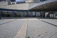 a person sitting at the bench in front of a mall that is empty of people