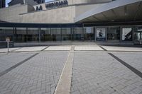 a person sitting at the bench in front of a mall that is empty of people