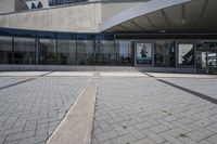 a person sitting at the bench in front of a mall that is empty of people