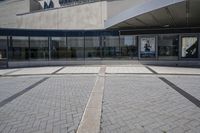 a person sitting at the bench in front of a mall that is empty of people