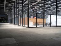 a view of an empty building from the inside at night with chairs and tables outside