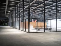 a view of an empty building from the inside at night with chairs and tables outside