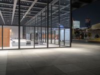 a building with a lot of windows and concrete flooring, at night time, in front of it