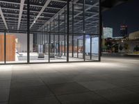 a building with a lot of windows and concrete flooring, at night time, in front of it