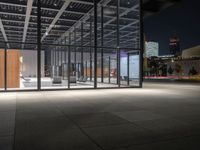 a building with a lot of windows and concrete flooring, at night time, in front of it