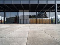 the inside of a glass covered building with a concrete floor and sky in background and the door way to it