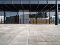 the inside of a glass covered building with a concrete floor and sky in background and the door way to it