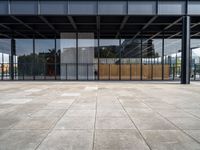 the inside of a glass covered building with a concrete floor and sky in background and the door way to it