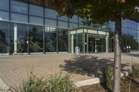 a sidewalk with trash cans next to an office building and trees on the outside side