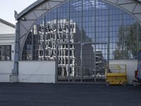 a couple of vehicles that are parked near a building by a big glass building with a sign on it