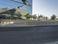 this empty parking lot is located at the corner of a modern, glass building with reflections on the sides