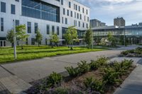 a city street surrounded by grass and tall buildings at the end of a street there is a paved pathway in front of the building