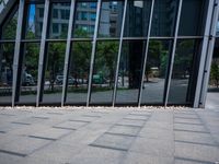 the sidewalk is clean and empty by the glass walls of a building in the city