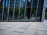 the sidewalk is clean and empty by the glass walls of a building in the city