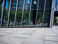 the sidewalk is clean and empty by the glass walls of a building in the city