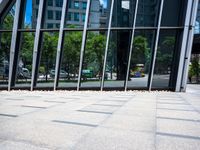 the sidewalk is clean and empty by the glass walls of a building in the city