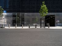 an empty street in front of a building and a parking meter next to it's entrance