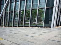 a yellow fire hydrant in front of a tall building with glass windows and gravel