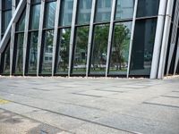 a yellow fire hydrant in front of a tall building with glass windows and gravel