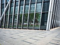 a yellow fire hydrant in front of a tall building with glass windows and gravel