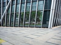 a yellow fire hydrant in front of a tall building with glass windows and gravel