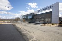 a large glass building with a sign on it that reads friendship service is next to a fork and a forklift