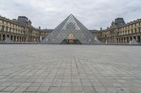 the large glass pyramid is at the entrance of a large building with a big courtyard