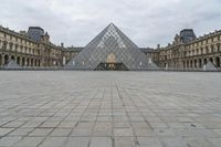 the large glass pyramid is at the entrance of a large building with a big courtyard