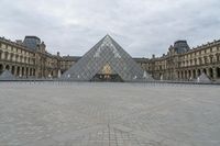 the large glass pyramid is at the entrance of a large building with a big courtyard