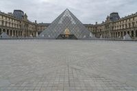 the large glass pyramid is at the entrance of a large building with a big courtyard