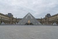 the large glass pyramid is at the entrance of a large building with a big courtyard