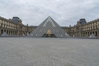 the large glass pyramid is at the entrance of a large building with a big courtyard