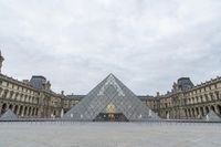 the large glass pyramid is at the entrance of a large building with a big courtyard