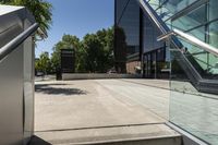 an outside staircase with glass railing and a building behind it on a sunny day with blue sky