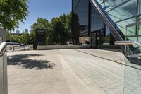 an outside staircase with glass railing and a building behind it on a sunny day with blue sky