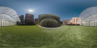 a large building with a glass structure in the center, in an area with artificial grass and lots of windows