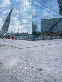 some kind of glass building near a brick paved area with a red fire hydrant