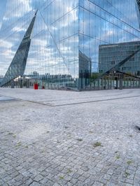 some kind of glass building near a brick paved area with a red fire hydrant