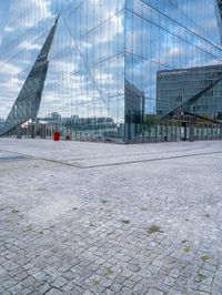 some kind of glass building near a brick paved area with a red fire hydrant