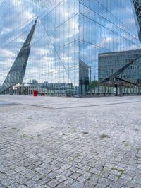 some kind of glass building near a brick paved area with a red fire hydrant